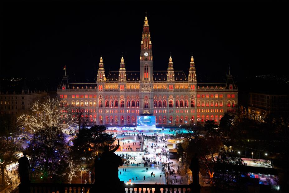 Abendlicher Blick auf die Eisfläche auf dem Wiener Rathausplatz mit beleuchtetem Rathaus im Hintergrund