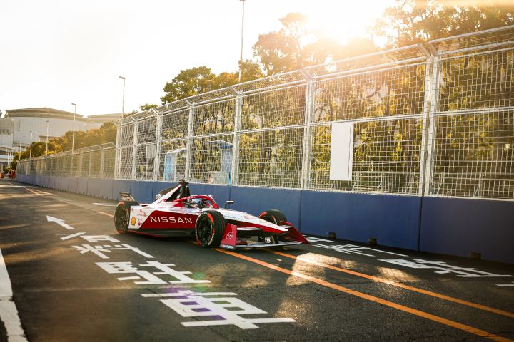 De Nissan raceauto staat op het asfalt geparkeerd naast de omheining van de racebaan
