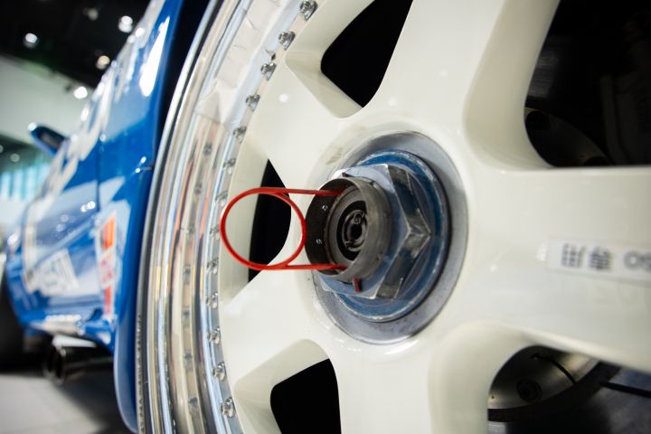 A close up of a white race car wheel installed on a blue NISMO GT‑R.