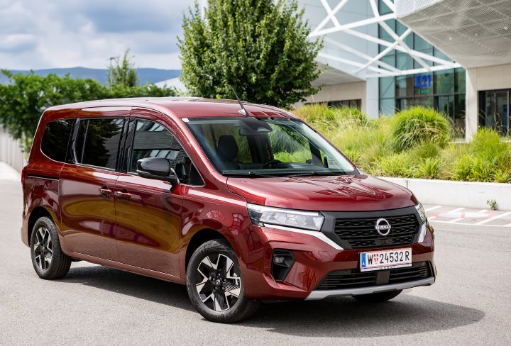 Roter Nissan Townstar Evalia Kombi, Front-/Seitenansicht statisch vor einem Bürogebäude
