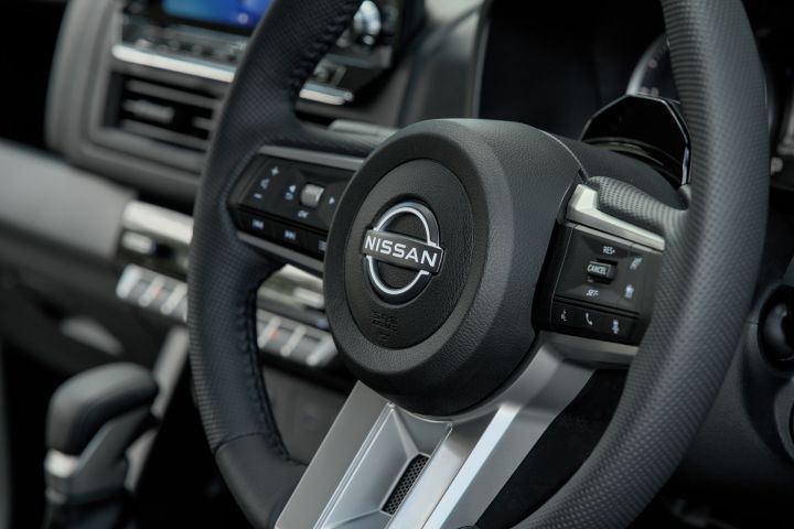 2026 Nissan Navara ST dual cab ute finished in Summit Silver with a close interior view of the Nissan steering wheel, multifunction controls and dashboard trim.