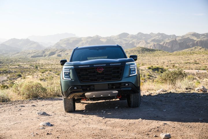 Front view of a 2025 Nissan Armada PRO-4X parked on arid terrain on a bright and cloudless day.