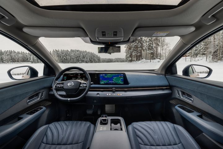 Interieur des Elektroauto Nissan Ariya e‑4ORCE mit blauer Nappa-Leder-Ausstattung, Blick auf die vorderen Sitze und das Cockpit, durch die Fenster sieht man eine Schneelandschaft