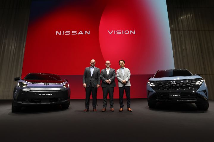 ผู้บริหารยืนบนเวทีหน้าฉาก “Nissan Vision” ระหว่างรถคอนเซ็ปต์นิสสันสองคันในงาน