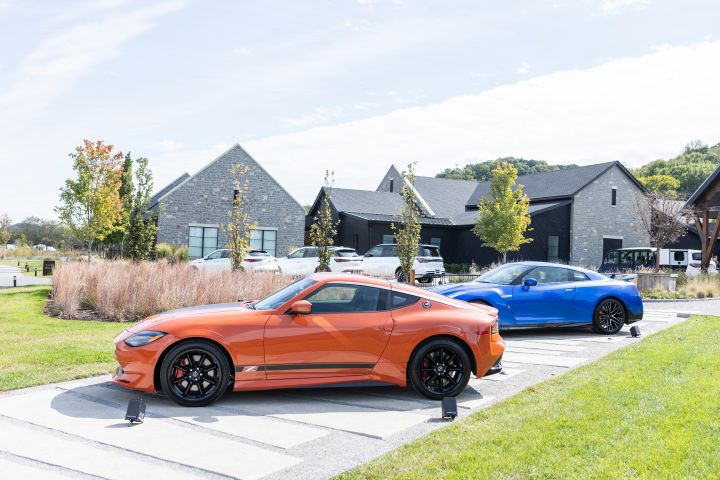A Nissan Z and GT‑R parked at a left 3/4 angle in front of a black venue building.