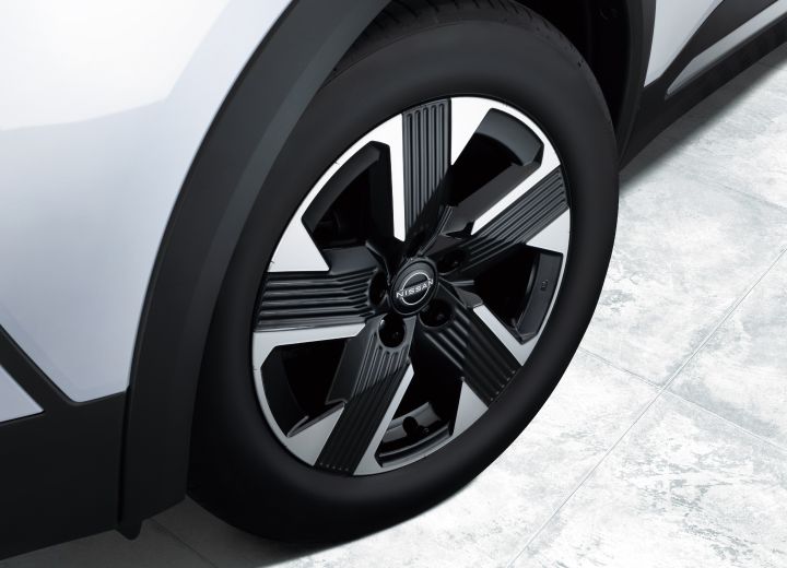Close-up of the wheel of a white Nissan Kicks. The vehicle faces right, clearly showing the wheel shape and tire.