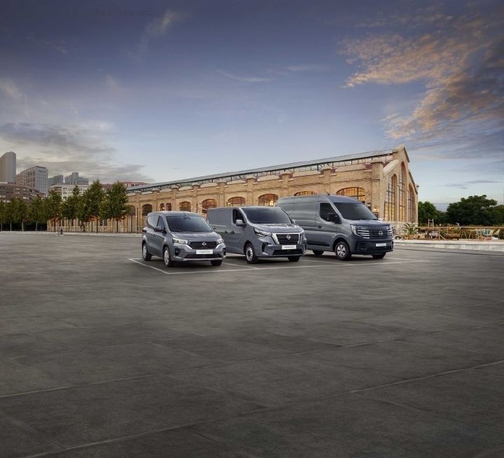 Front exterior view of three metallic grey-coloured Nissan vans in an empty car park setting