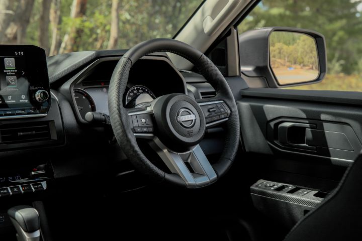 2026 Nissan Navara ST dual cab ute finished in Summit Silver shown from the driver’s seat, highlighting the steering wheel, gauge cluster and door switch panel.