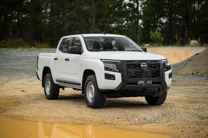 2026 Nissan Navara SL dual cab ute finished in Alpine White presented from a front three-quarter perspective, featuring the black grille, steel wheels and raised utility stance.