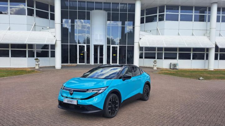Blauwe Nissan LEAF driekwart voor, geparkeerd voor een gebouw