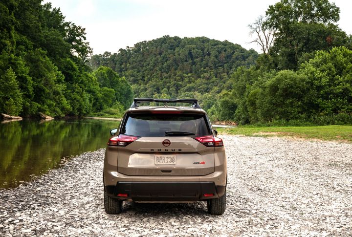 Rear view of the 2025 Nissan rogue parked on rocks next to a creek surrounding woods