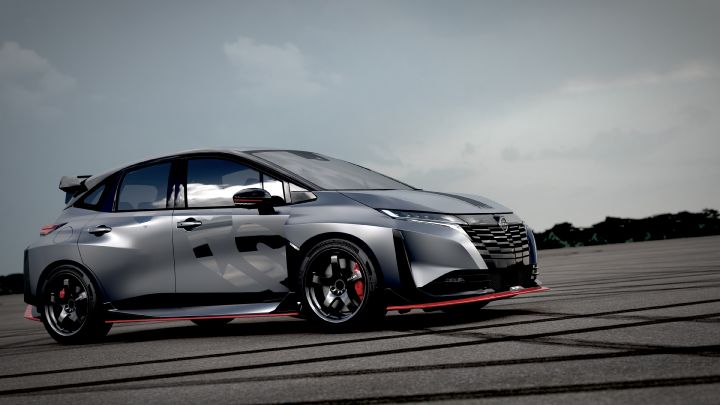 A silver and black two-tone sports car, the Aura Nismo RS Concept, parked on an outdoor skid pad in a diagonal view. The vehicle faces toward the left front, featuring a low stance and a large rear wing. The wheels are black with visible red brake calipers. The side displays a light gray 'RS,' and a red accent line runs along the lower body. The background shows a cloudy sky and distant trees, with tire marks visible on the asphalt surface.