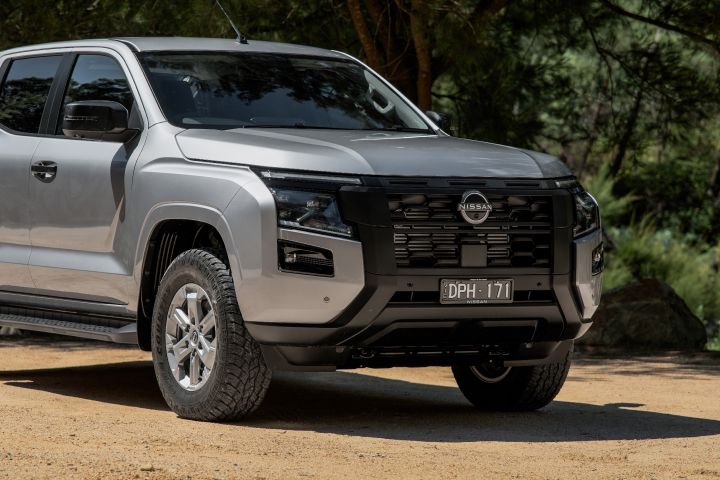 2026 Nissan Navara ST dual cab ute finished in Summit Silver shown in a low front-end close-up with black grille detailing, bumper design and front wheel.