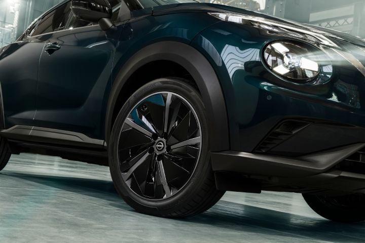 Close-up view of the Nissan JUKE Pulse front wheel and headlight, highlighting the asymetrical alloy wheel design and sculpted bodywork.