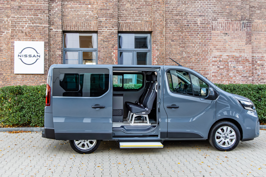 Seitenansicht auf den Primastar FlexVan mit geöffneter Seitentür vor einer grünen Hecke und einem Backsteingebäude