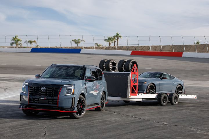 A Nissan Armada pulling a Nissan Z on a racetrack.