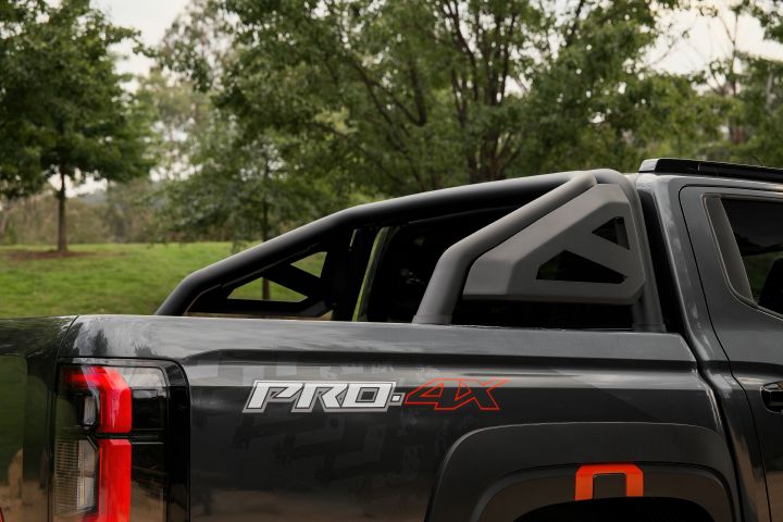 2026 Nissan Navara PRO-4X finished in Boulder Grey showing the rear tub side with PRO-4X decal, sports bar, tail-light edge and red-accented fender flare.