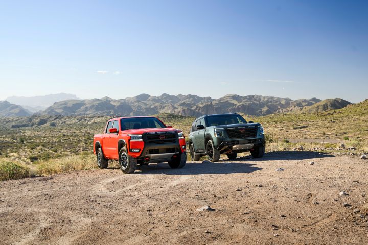 The 2025 Nissan Frontier PRO-4X and 2025 Nissan Armada PRO-4X parked together on rocky terrain with mountains behind on a sunny day.
