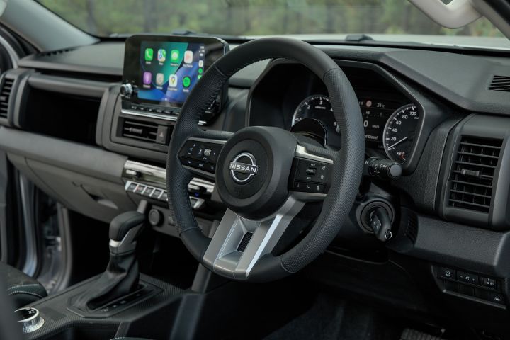 2026 Nissan Navara ST dual cab ute finished in Summit Silver shown with a close interior detail of the steering wheel, dashboard trim and control stalks.