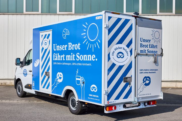 Blick von schräg hinten auf den parkenden Nissan Interstar-e mit blau-weiß beklebtem Bäckereikoffer