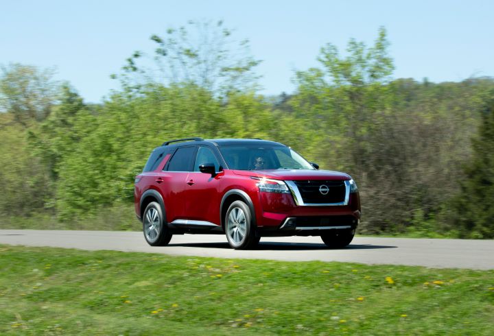 Red Pathfinder driving left to right down a road