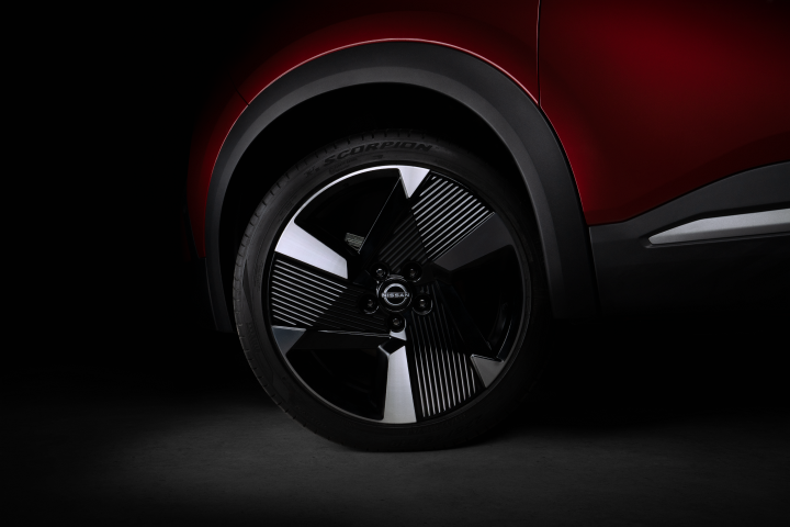 Vista lateral do novo Nissan Kicks destacando a traseira do carro com pintura em vermelho metálico e teto preto. O nome “KICKS” aparece na janela traseira, com linhas aerodinâmicas e estilo arrojado
