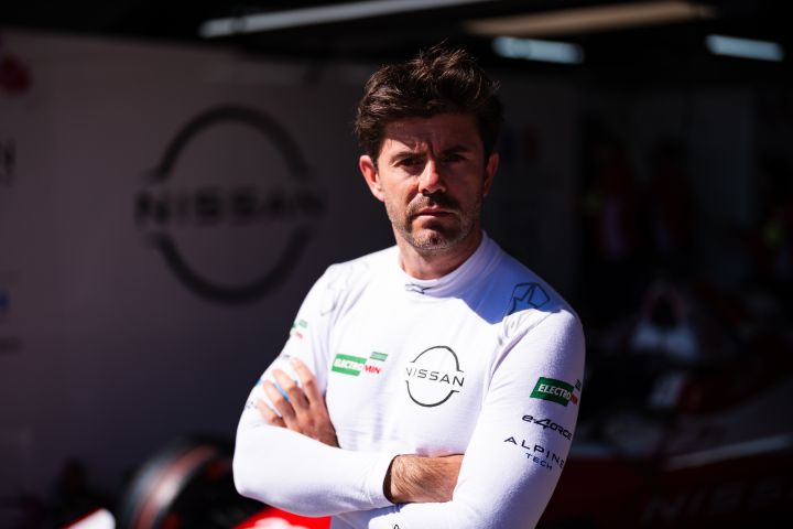 Norman Nato steht mit verschränkten Armen und in seinem weißen Nissan Shirt vor der Teamgarage und schaut zu.