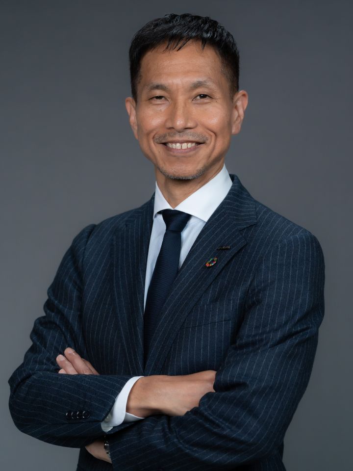 Portrait of Toru Ihara with his arms folded (suit, tie, NISSAN corporate pin and SDGs badge) (smiling)