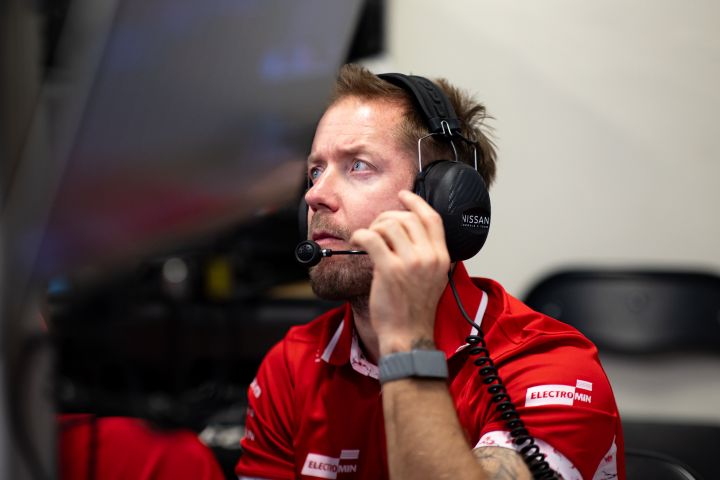 Sam Bird, Ersatz- und Entwicklungsfahrer des Nissan Formula E Teams, verfolgt das Geschehen auf der Rennstrecke mit Kopfhörern und einem roten Nissan Formula E Team-Poloshirt.