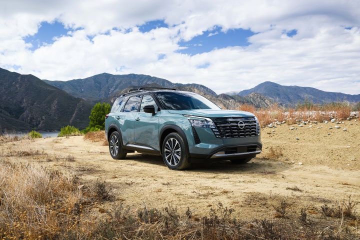 Front right 3/4 view of the 2026 Nissan Pathfinder pared on a dirt road with clouds behind.