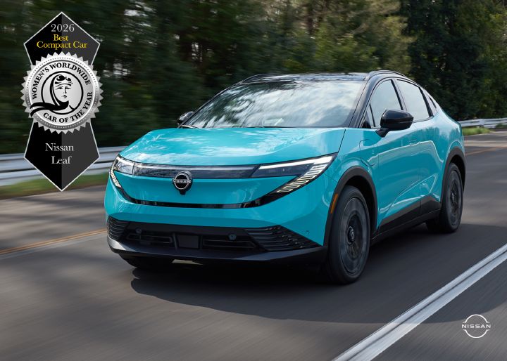Front left 3/4 view of a 2026 Nissan LEAF driving along a road with an award graphic in the upper left of the image.