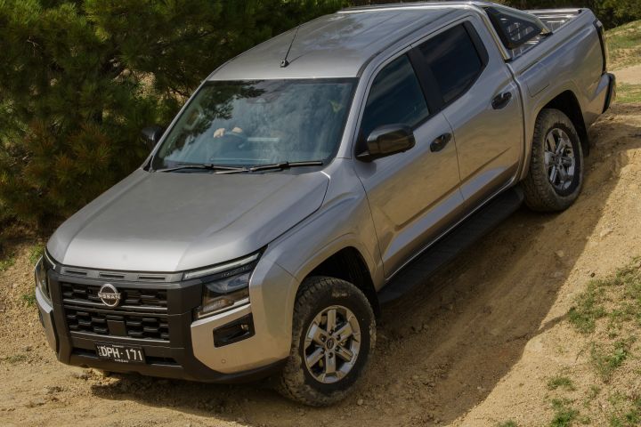 2026 Nissan Navara ST dual cab ute finished in Summit Silver photographed from the front-left climbing a sandy off-road slope.