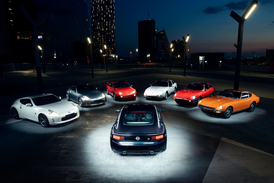 A rear view of the 2026 Nissan Z Heritage Edition in Midnight Purple at dusk, positioned in the centre of a circle of historic Nissan Z models under rooftop lighting.
