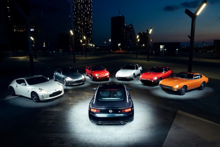 A rear view of the 2026 Nissan Z Heritage Edition in Midnight Purple at dusk, positioned in the centre of a circle of historic Nissan Z models under rooftop lighting.