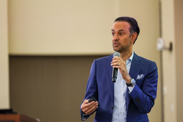 A man looking intently at an audience with a microphone held up to his face.