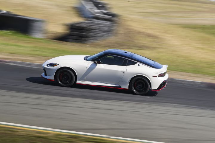 A white 2027 Nissan Z NISMO Manual Transmission driving on a racetrack, the background is blurred.