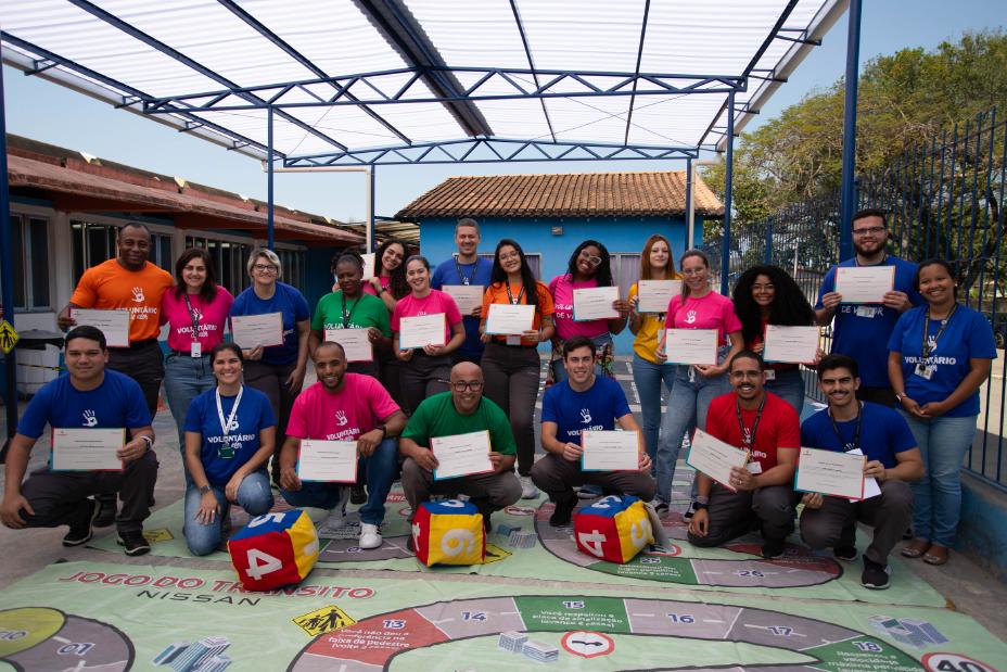 Voluntários da Nissan posam com idosos em uma praça segurando ceritficados de participação no evento