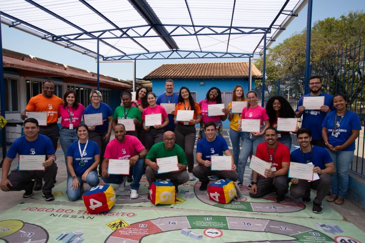 Voluntários da Nissan posam com idosos em uma praça segurando ceritficados de participação no evento