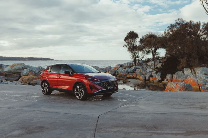 A 2026 Qashqai e‑POWER model stationary by rocks and the sea.