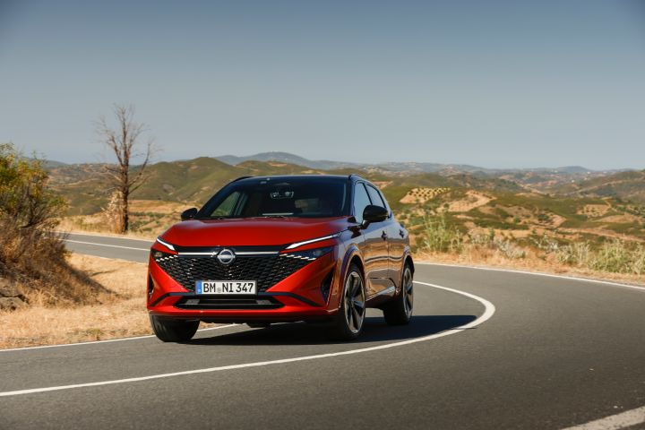 Ein roter Nissan Qashqai biegt auf einer portugiesischen Landstraße um eine enge Kurve